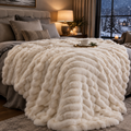 Ivory ruched faux fur weighted throw on a bed on a snowy winter night